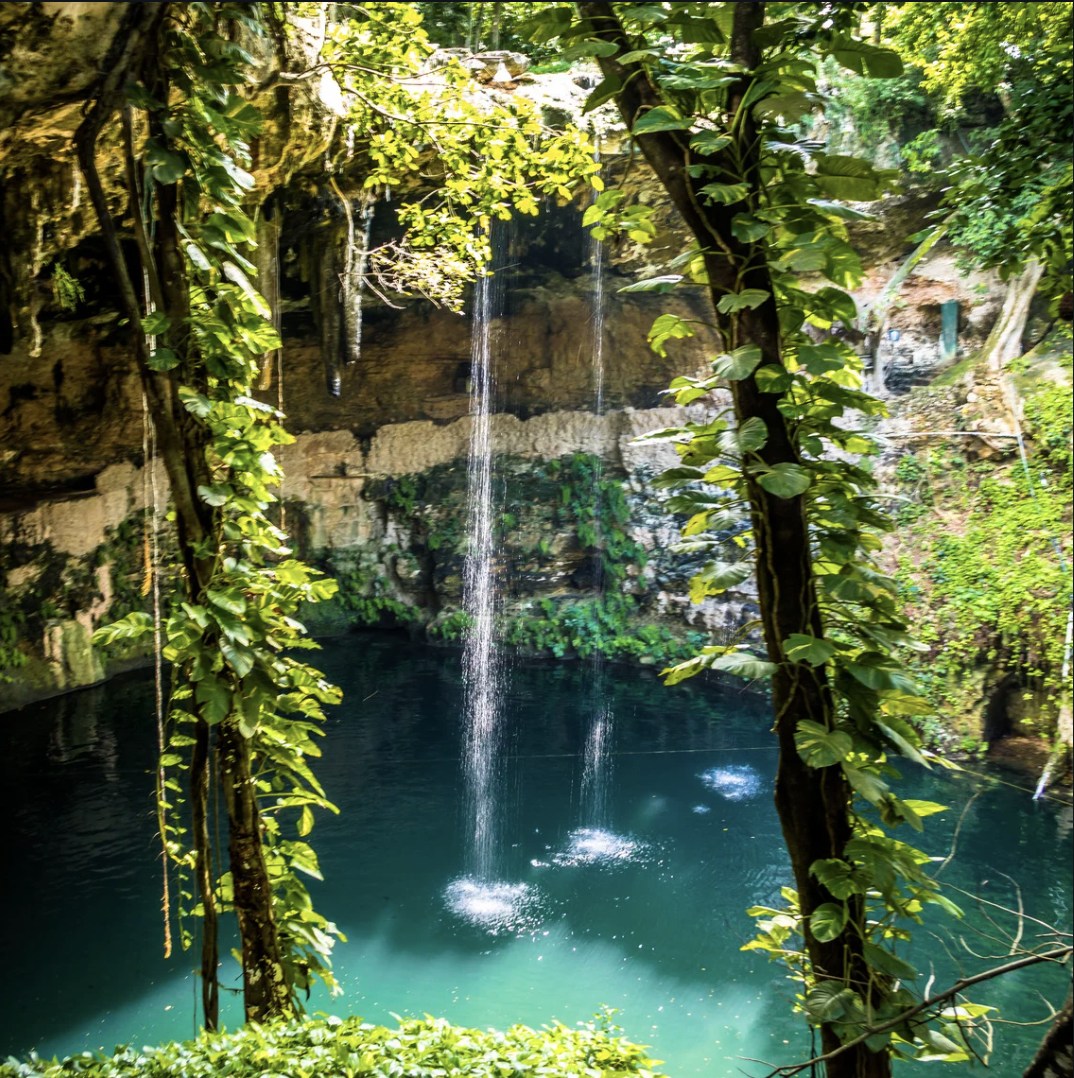 Crystal clear cenote with waterfall in the Yucatán jungle