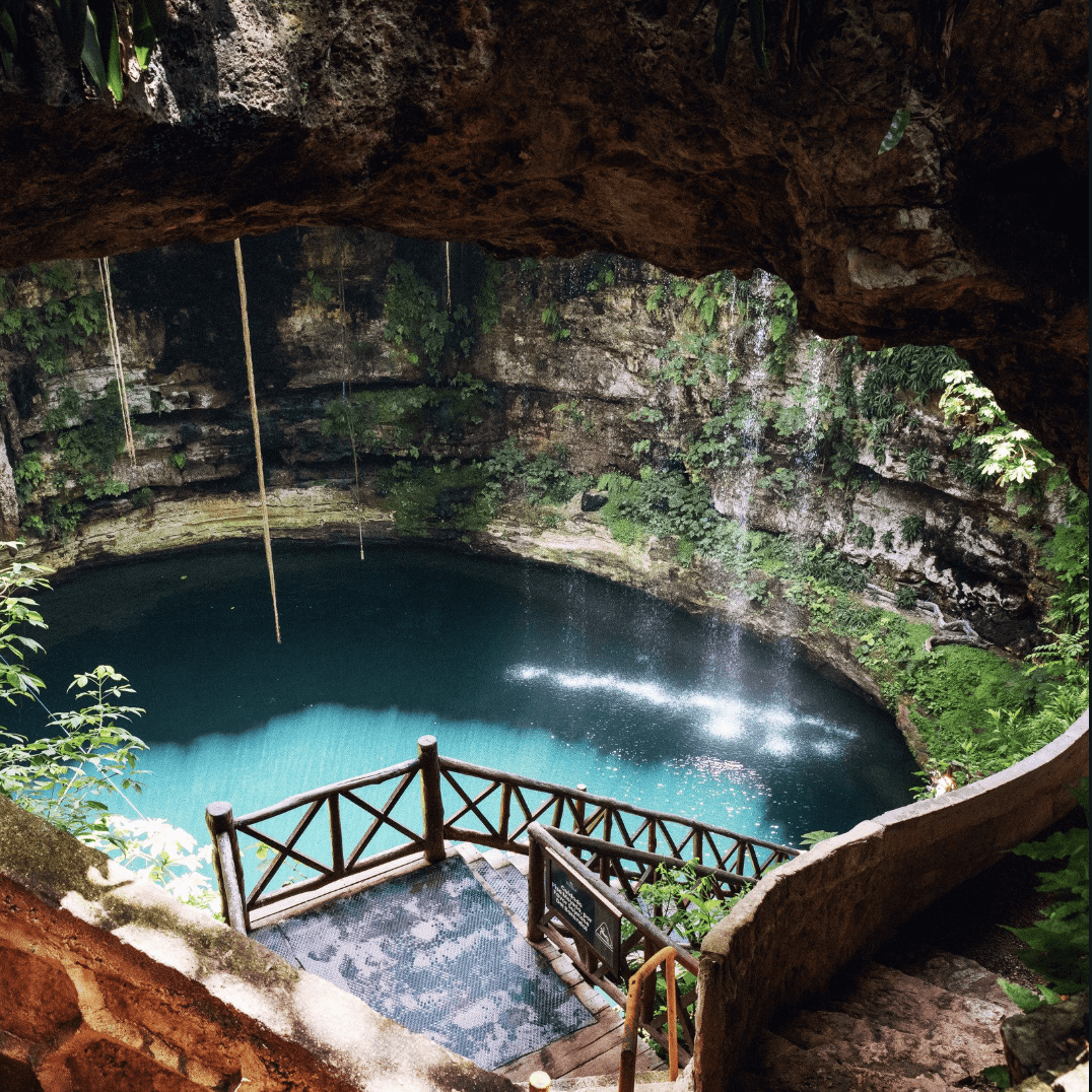 Open cenote with wooden stairs and turquoise water
